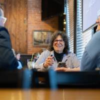 Group of guests at event sitting at table and laughing with each other